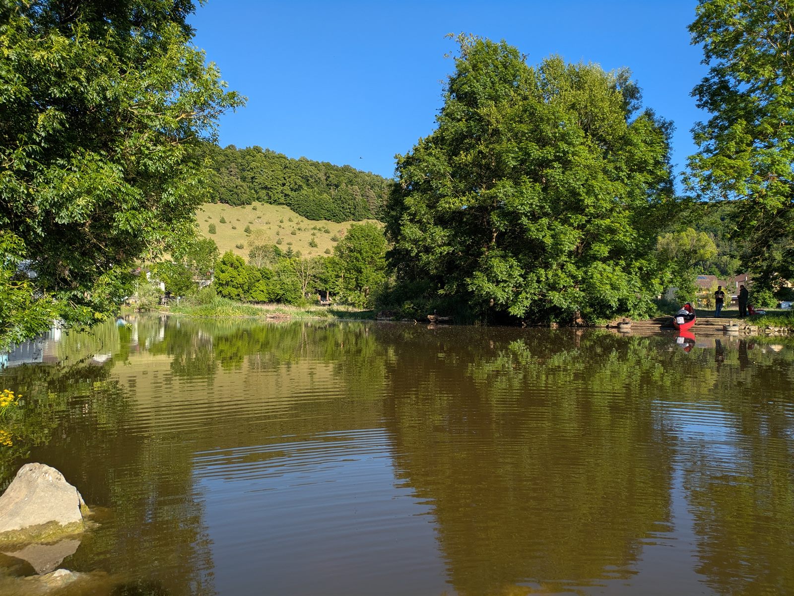 Ruhiger Fluss vor sanften, grünen Hügeln