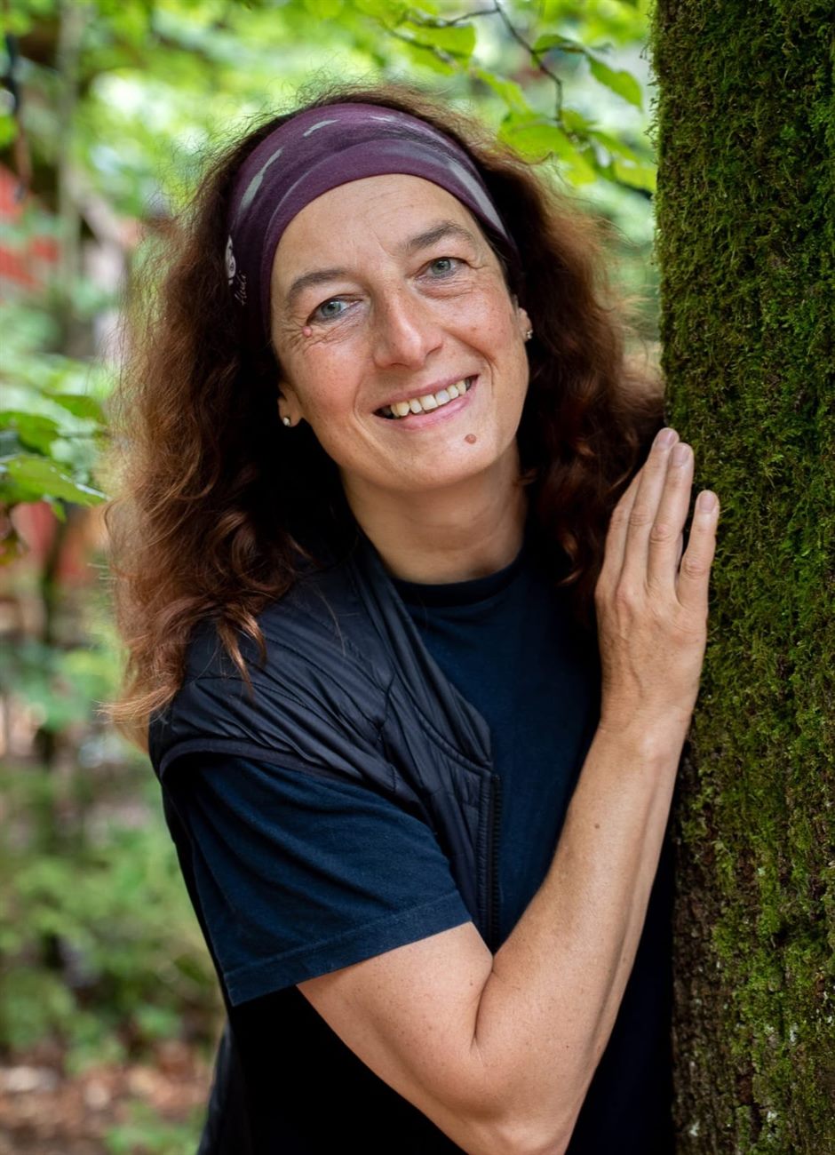 Heidi Michele im Wald, an einen Baumstamm gelehnt